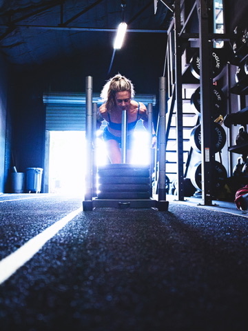 Athlete driving a weighted sled down a turf lane at Dallas Performance Systems